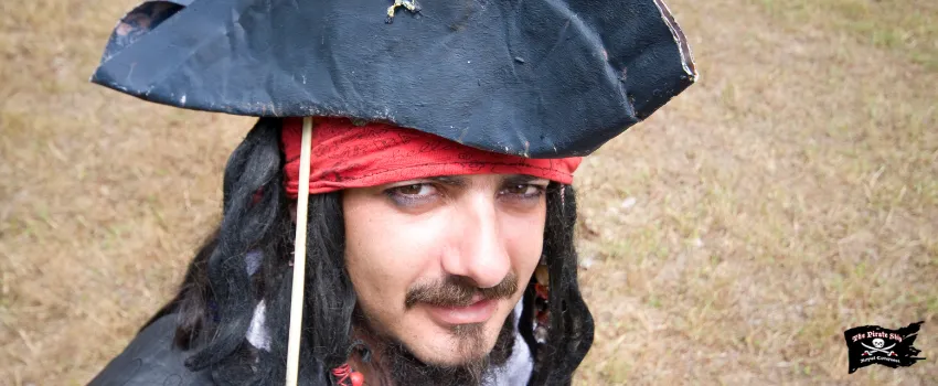 SST - A man dressed up as a pirate sitting wearing eyeliner and black hat